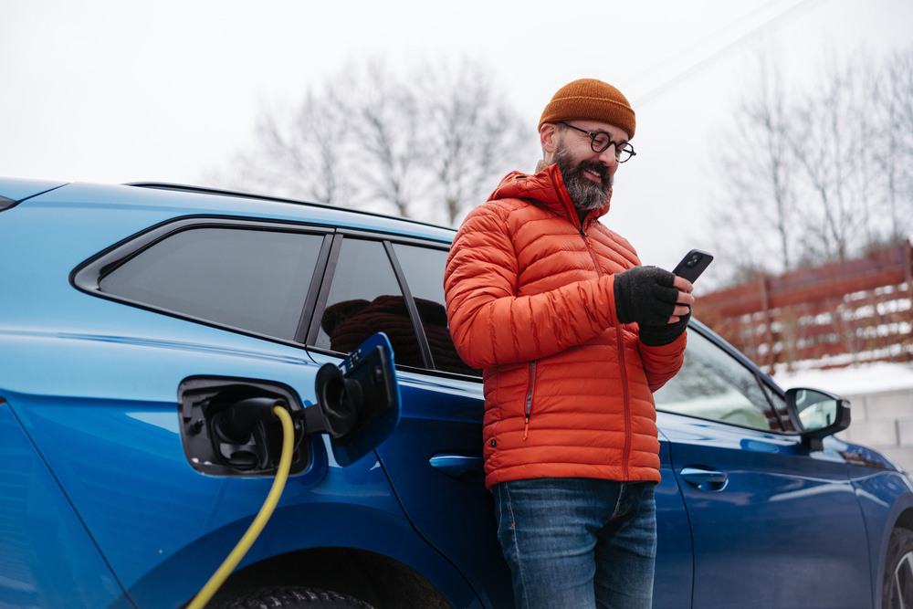 Mężczyzna w czasie ładowania pojazdu elektrycznego